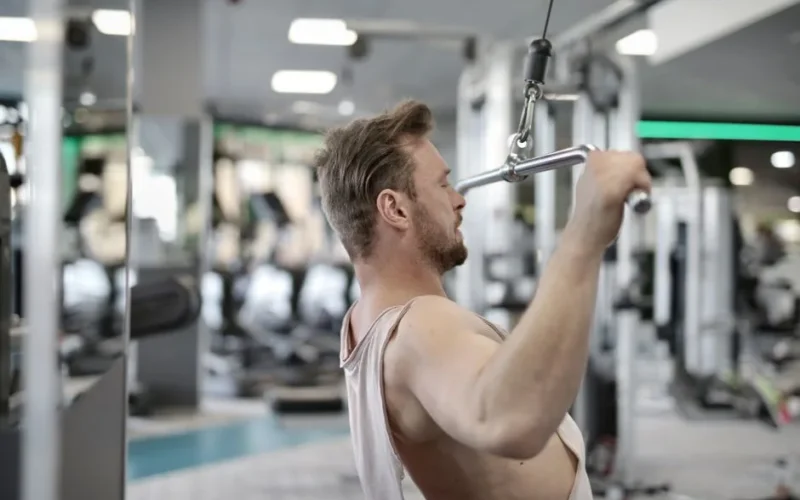 Focused man performing lat pulldown exercise indoors.