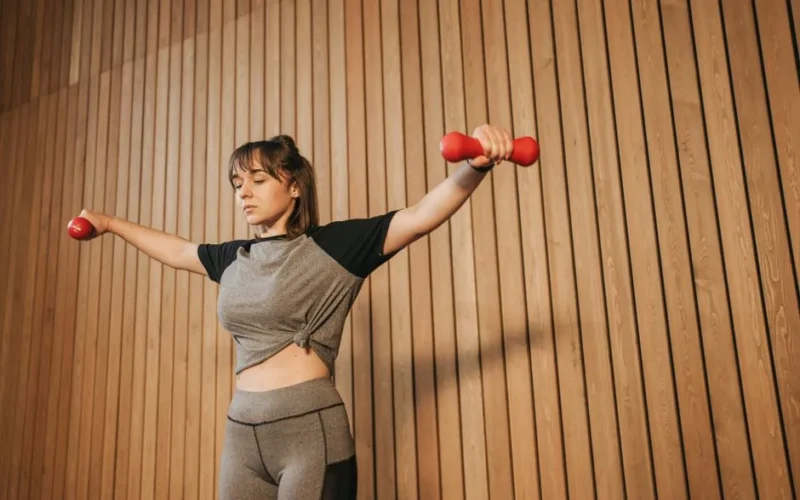 Caucasian woman in activewear lifting dumbbells for fitness training.