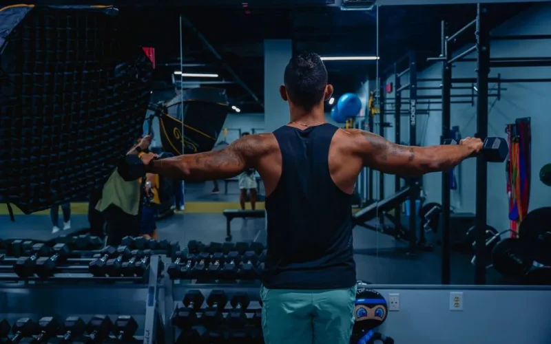 Adult male working out with dumbbells in a gym, focused on building strength and fitness.
