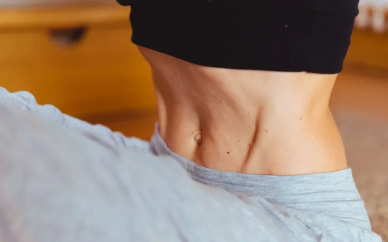 Close-up of a fit person's torso wearing sportswear, emphasizing toned muscles.