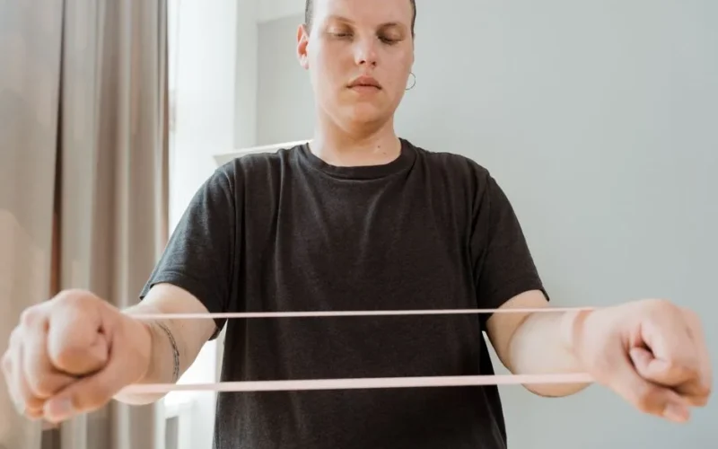 Man exercising with a resistance band indoors, promoting home fitness and wellness.