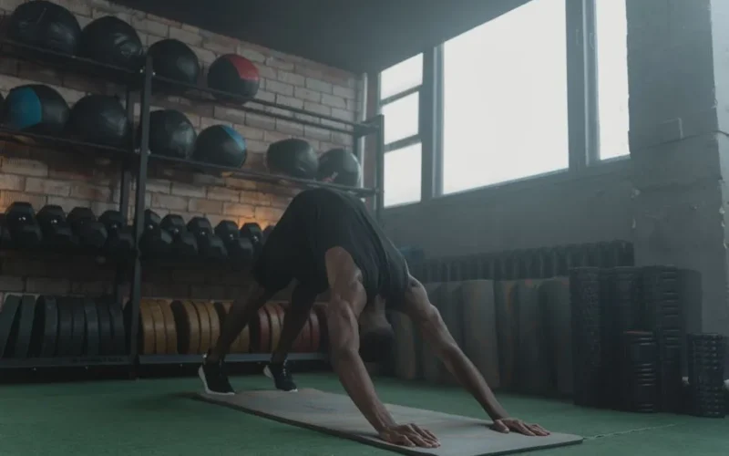 Man performing fitness workout on yoga mat in gym. Focus on strength and body posture.