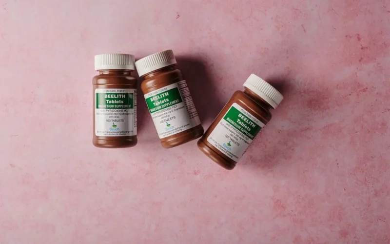 Three brown bottles of magnesium tablets on a soft pink background, ideal for health-themed content.