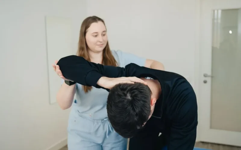 A physiotherapist aids a patient in a stretching exercise for rehabilitation.