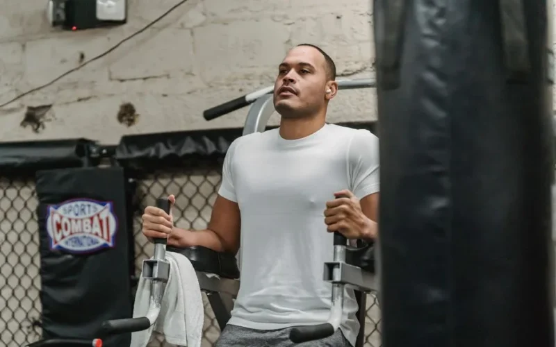 Focused sportsman doing knee to chest exercise for abdomen muscles on machine during intense workout in modern gym