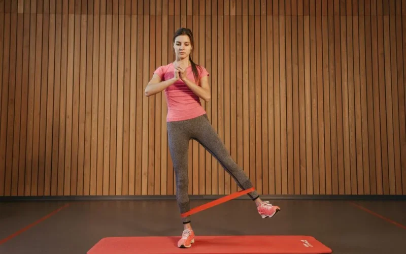 A woman performs leg exercises with a resistance band at a gym, promoting fitness and healthy living.
