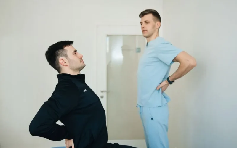 A physiotherapist instructs a patient on back exercises in a clinic setting.