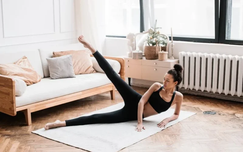 A woman exercises, performing yoga in a stylish living room with soft natural lighting.