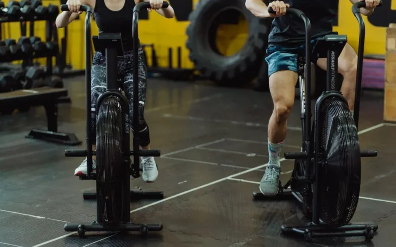 Two people exercising on stationary bikes at a modern gym.