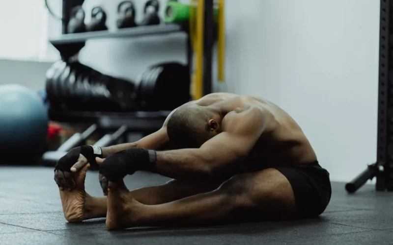 Man doing seated stretch in gym, emphasizing fitness and flexibility training.