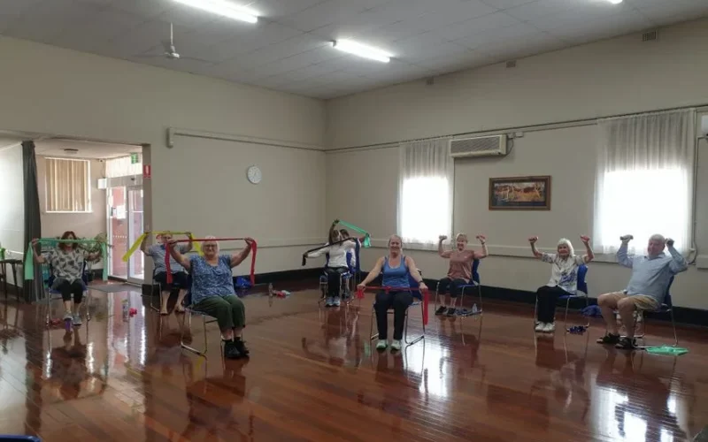 Active seniors engaging in a chair exercise class, promoting wellness and positive aging.