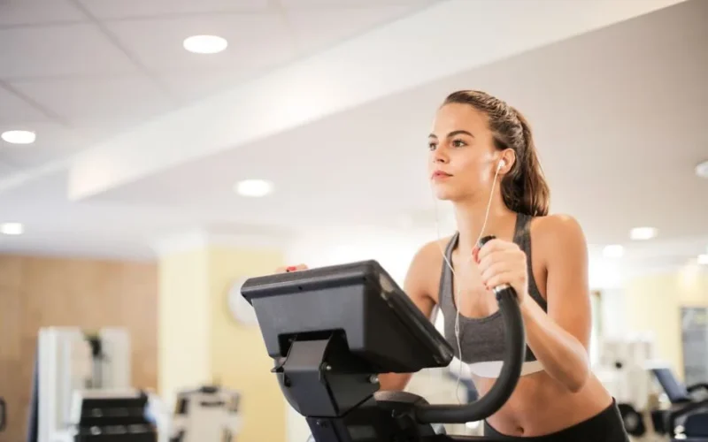 Woman in a gym focused on cardio exercise using elliptical machine. Healthy lifestyle and fitness concept.
