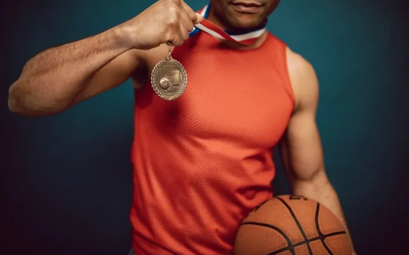 Man holding a medal and basketball, showcasing achievement in sports.