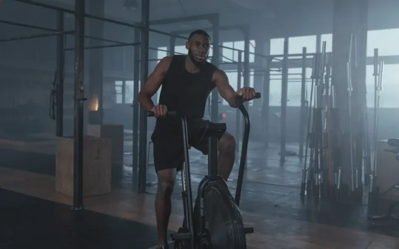 Focused man in gym working out on elliptical machine, promoting fitness and lifestyle.