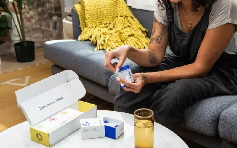 A woman sitting on a sofa examining nootropic supplements, promoting wellness and clarity.