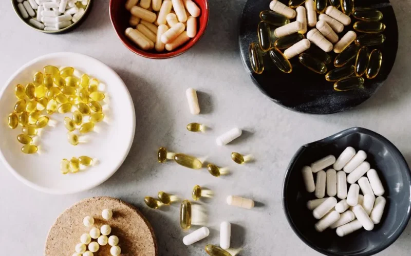 Various pills and supplements in bowls on a marble surface, ideal for healthcare contexts.