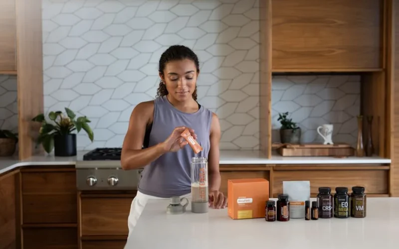 A woman uses essential oils and supplements in a contemporary kitchen for wellness.