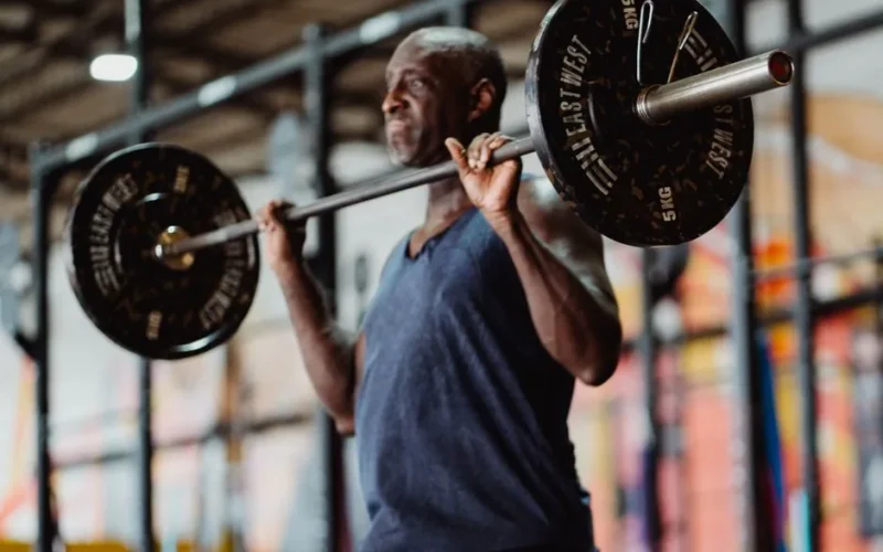A focused man lifting weights in a gym setting, demonstrating strength and fitness.
