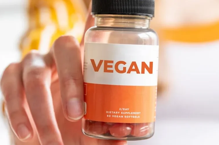 A detailed image of a hand holding a vegan supplement bottle, ideal for health and lifestyle themes.