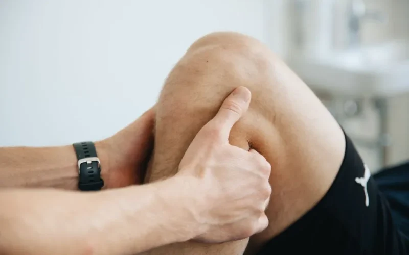 Close-up of a physiotherapist massaging a patient's knee during therapy.