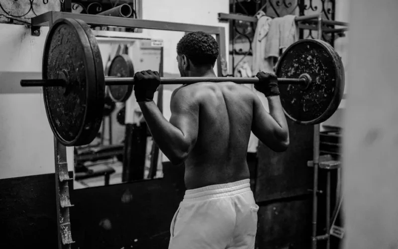 A determined man lifting weights in a gym, showcasing strength and fitness focus.