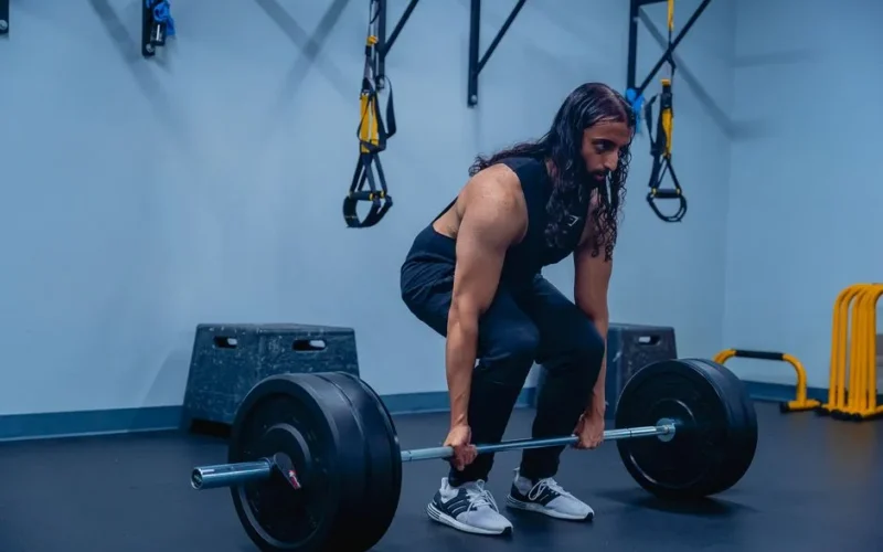 A man performing deadlifts in a gym, showcasing strength training and fitness routines.