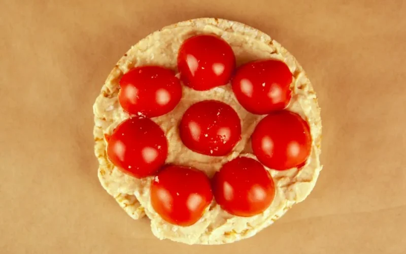 Delicious rice cake topped with hummus and juicy cherry tomatoes.
