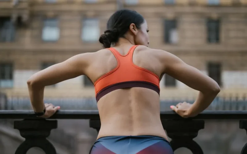 Back view of a woman in activewear working out outdoors on a balcony.