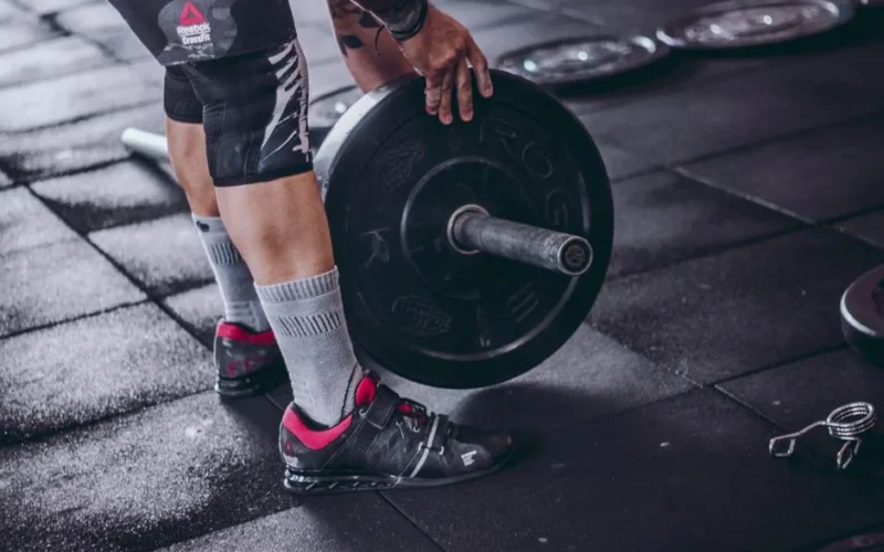 A focused man lifting a heavy barbell during weightlifting exercise in a gym.