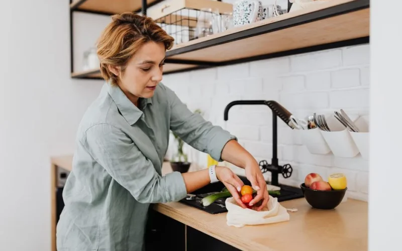 Woman preparing fresh vegetables in a sleek kitchen setting, showcasing culinary activities.