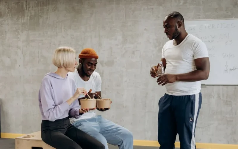 Three adults enjoy a nutritious meal together indoors, embracing a healthy lifestyle.