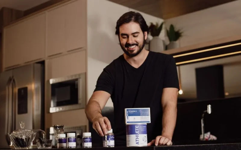 Smiling man arranging vitamin supplements on kitchen counter.