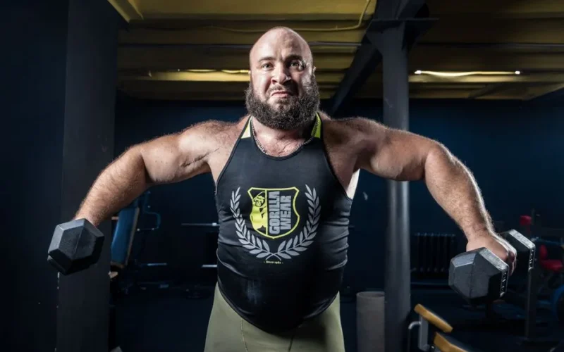 Strong bodybuilder lifting dumbbells in a gym, showcasing strength and determination.