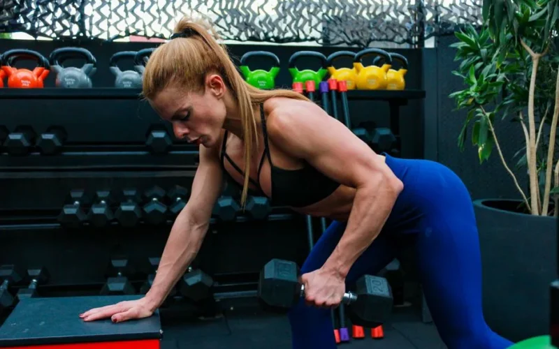 Woman exercising with dumbbells in gym. Focused on strength training and fitness.