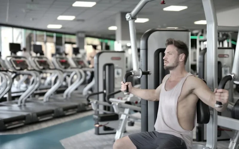 Man exercising on chest press machine in a modern gym, showcasing fitness and strength.
