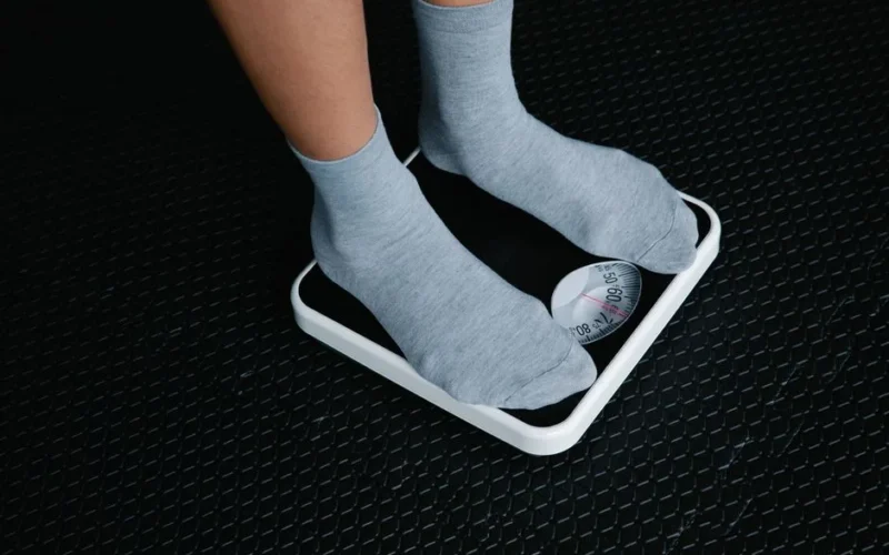 Close-up of feet in socks standing on a scale, focusing on weight measurement.