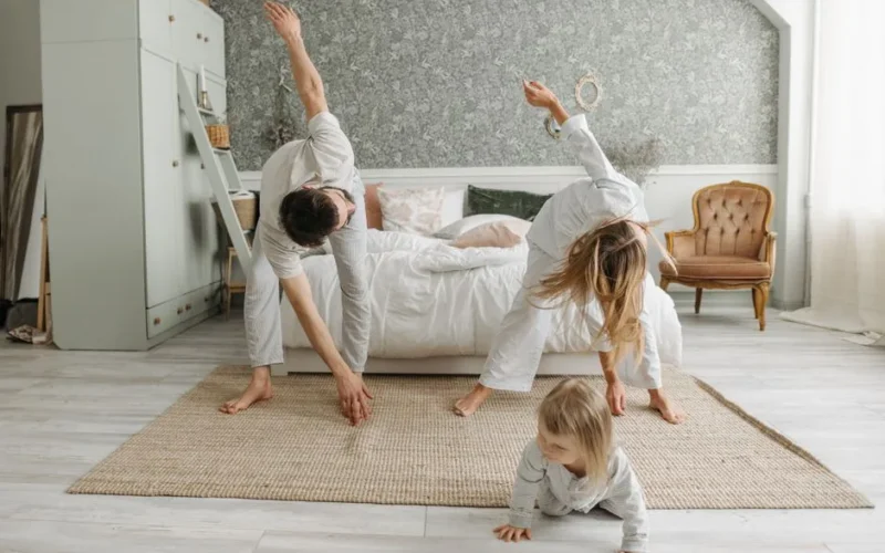 A family stretches together in a cozy bedroom, enjoying morning activities.