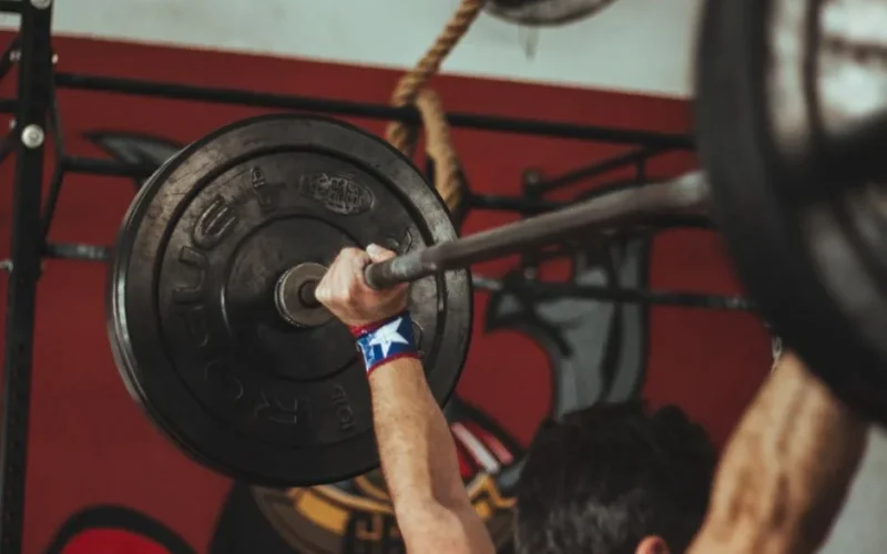 Athlete lifting heavy barbell during strength training session in gym.
