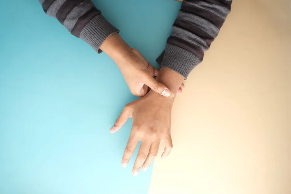 Close-up view of hands wearing striped long sleeves on a two-tone background.