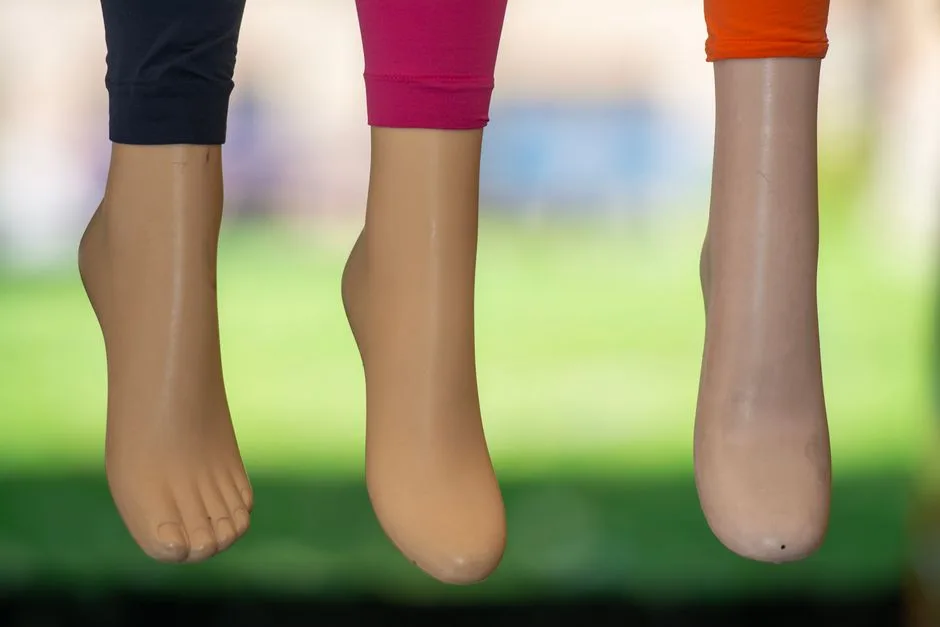Close-up of mannequin feet in blue, pink, and orange leggings against a green background.