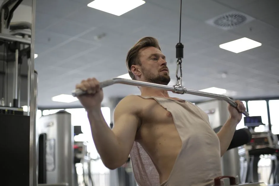 Focused man doing lat pulldown exercise in a modern gym setting.