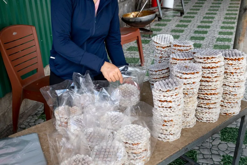 Crop unrecognizable female seller putting rice cakes with filling and chia seeds in plastic packs at desk