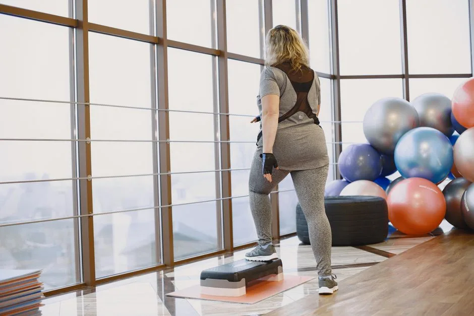 Back view of a woman exercising indoors with fitness equipment and step platform.