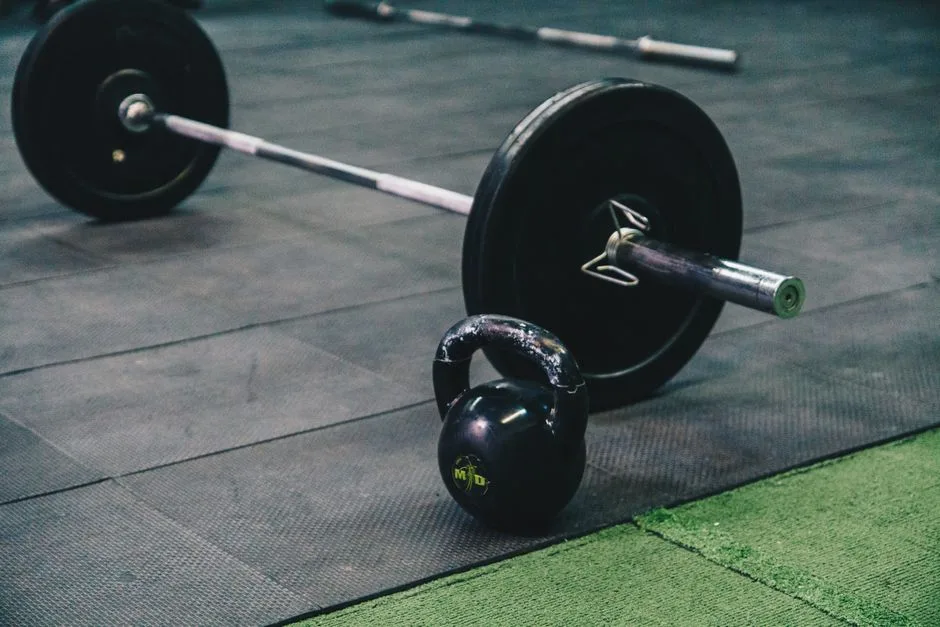 Barbell and kettlebell on gym floor, ideal for fitness and strength training themes.