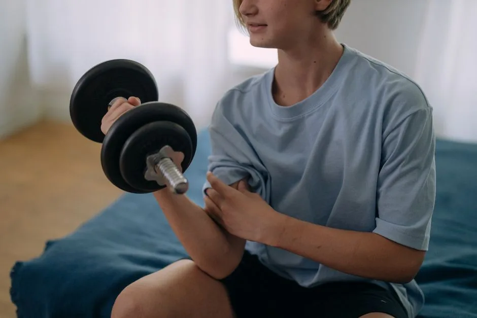 Teenage person lifting a dumbbell in a home setting, focused on fitness and health.
