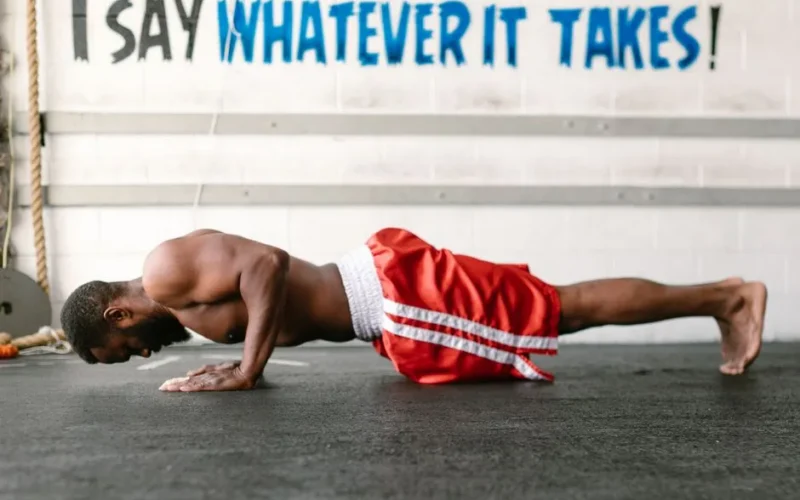 Athletic man doing push-ups indoors with motivational text.