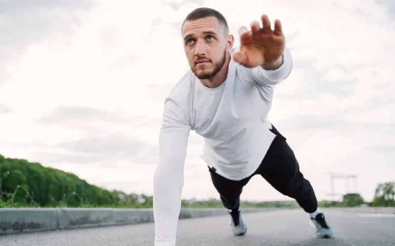 Adult male doing a core exercise on a rooftop in sportswear, promoting fitness and healthy living.