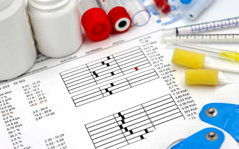 Arrangement of medical equipment, lab tests, and health data on a clinical table.
