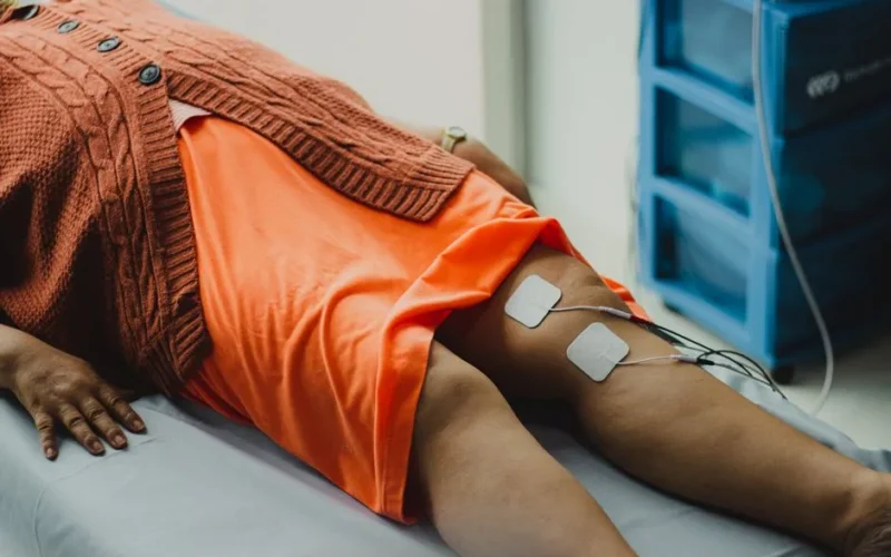 Close-up of a woman's legs during an electrical therapy session in a hospital setting.