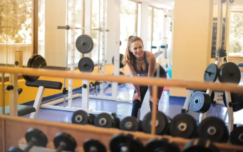 Fit woman in a gym with weights, showcasing strength and fitness lifestyle.